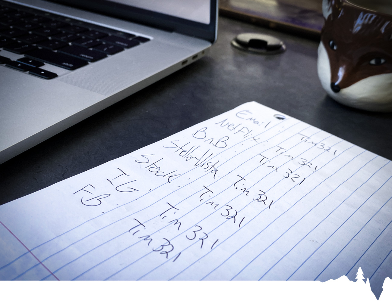 Handwritten notes on a lined paper next to a laptop and a ceramic fox mug.